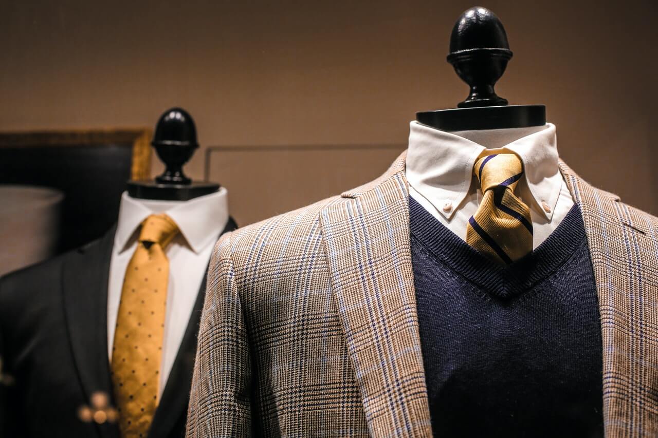 two non iron shirts with blazers and ties hanged on mannequins.