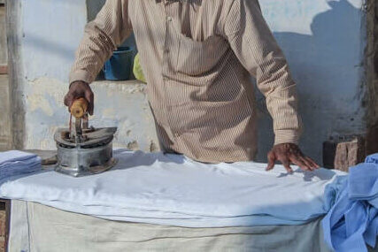 an old man ironing clothes with an old iron.