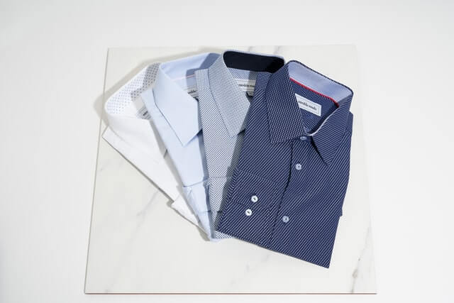 navy blue, light blue, and white color shirts lying on the white card board