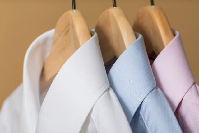 blue, pink, and white dress shirt hanging on hangars