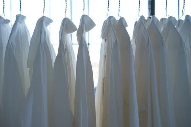 white dress shirts on hangars in front of bright sunny window.