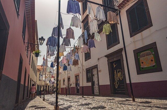 several non iron shirts drying in an alley on long rods