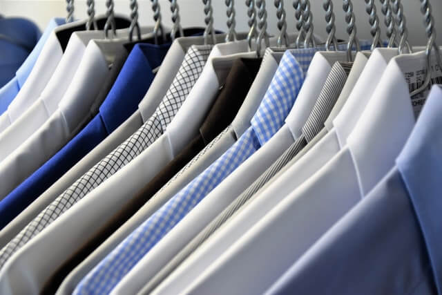 A number of dress shirts aligned together and hanged on hangars