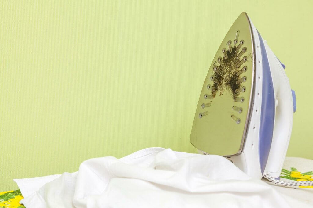a steam iron on an ironing board with a stain on the soleplate.