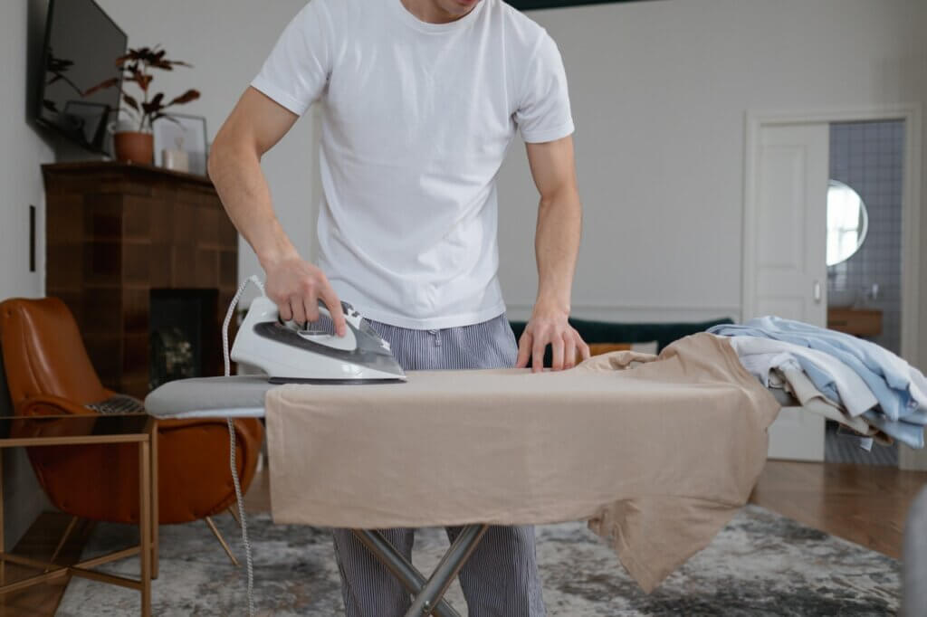 a guy steam ironing clothes on a board.