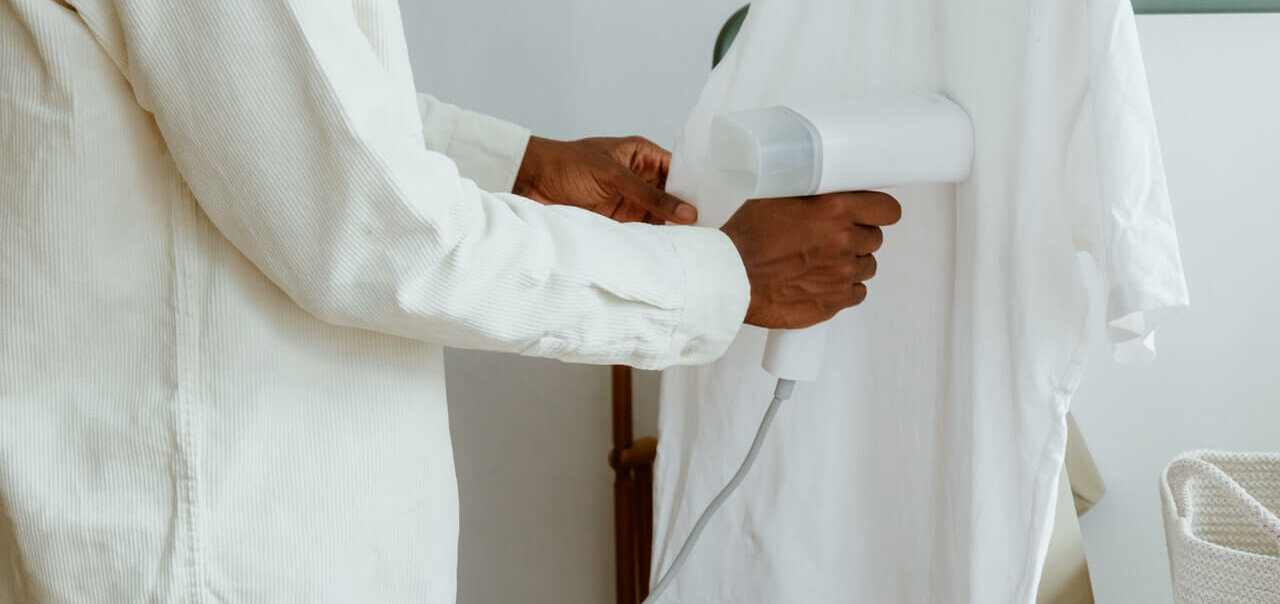 white steam iron removing the wrinkles from a white shirt through steam