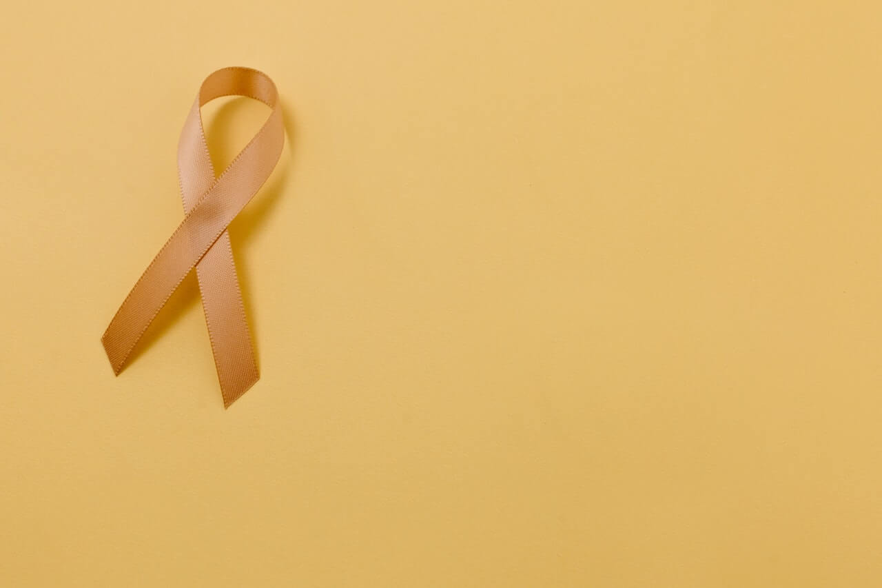 Yellow cancer awareness ribbon in a brown background