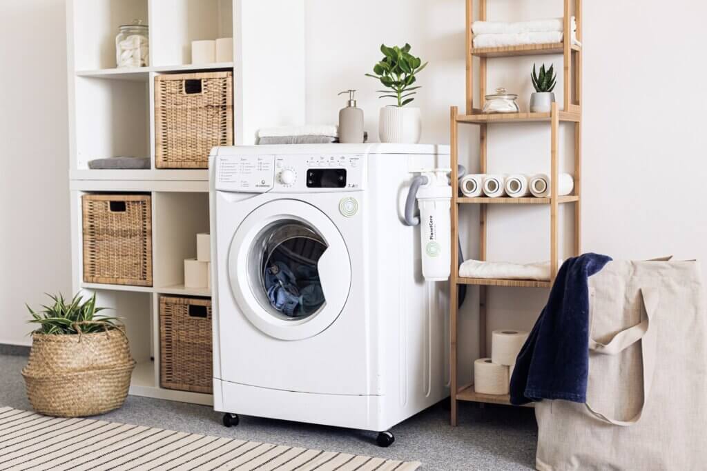 White washing machine with a front door and rolled towels on both sides.