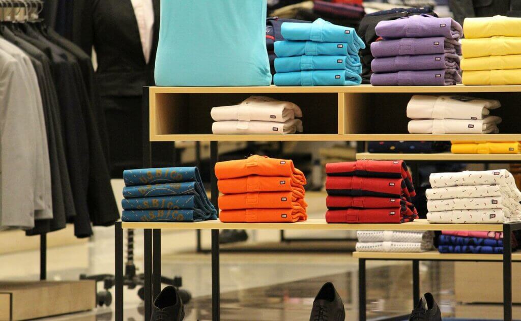 Piles of shirts in different colors in a shop